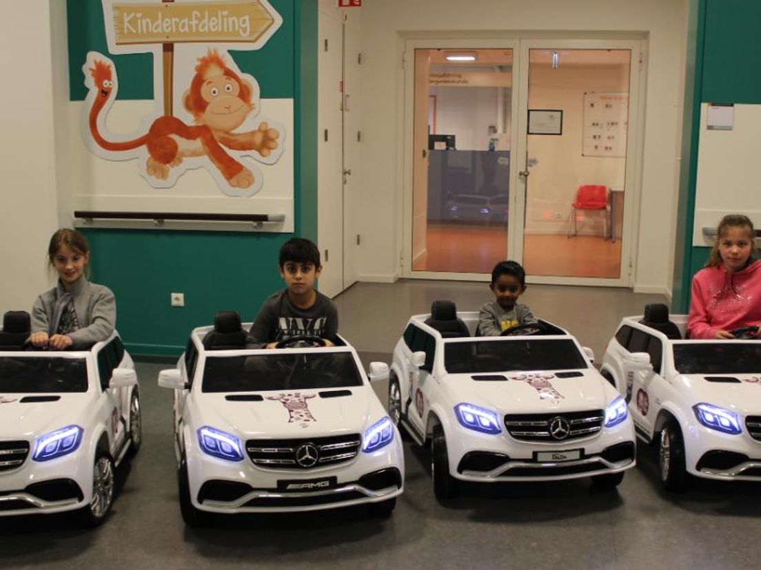 Vier kinderen testen de miniversie van de Mercedes in het Maasstad Ziekenhuis