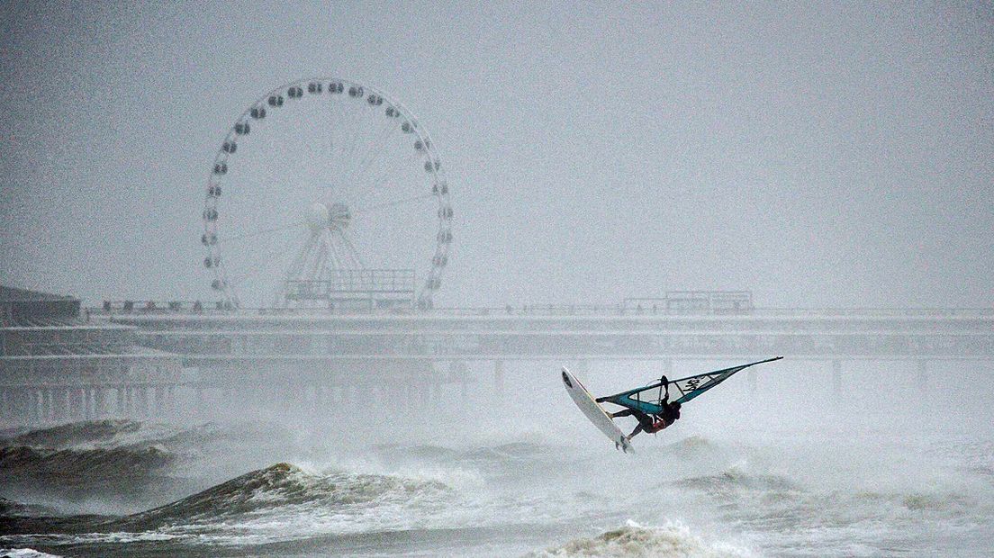 Een windsurfer trotseert de hoge golven op Scheveningen. 