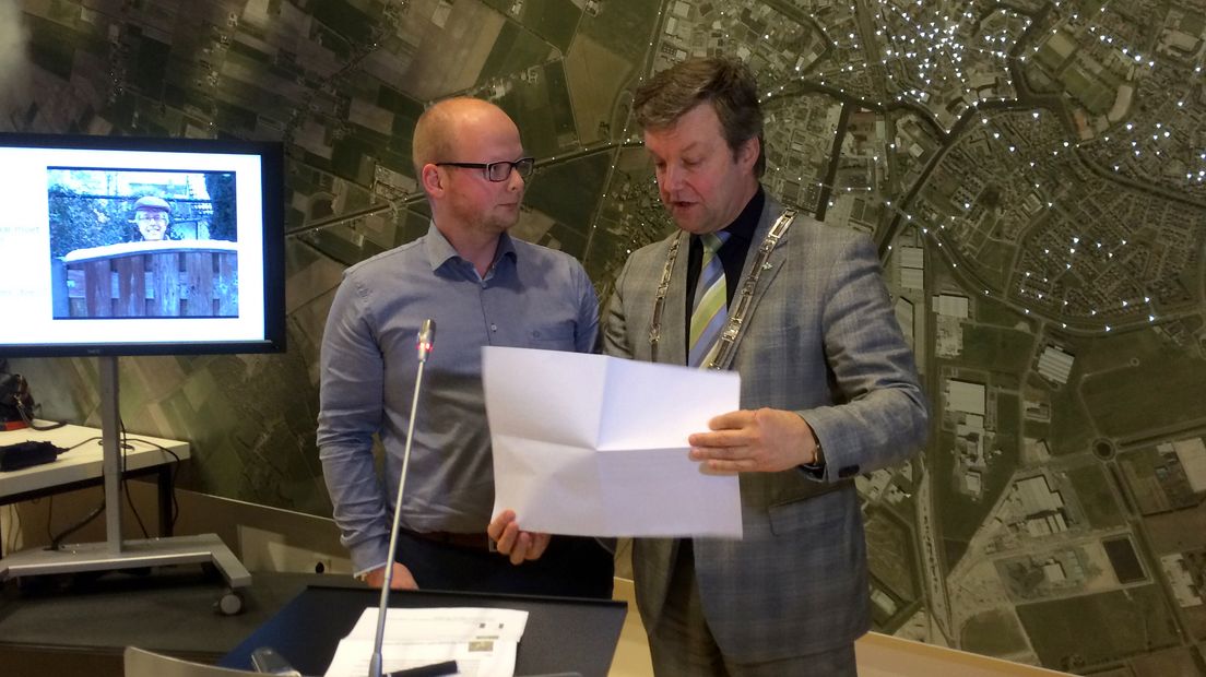 Frank Hoving van de initiatiefgroep biedt de resultaten van de enquête aan burgemeester Bouwmeester aan.