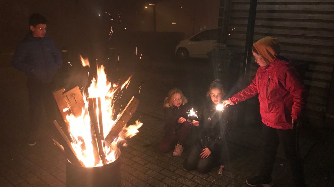 In Houten houden kinderen zich warm bij een vuurkorf.