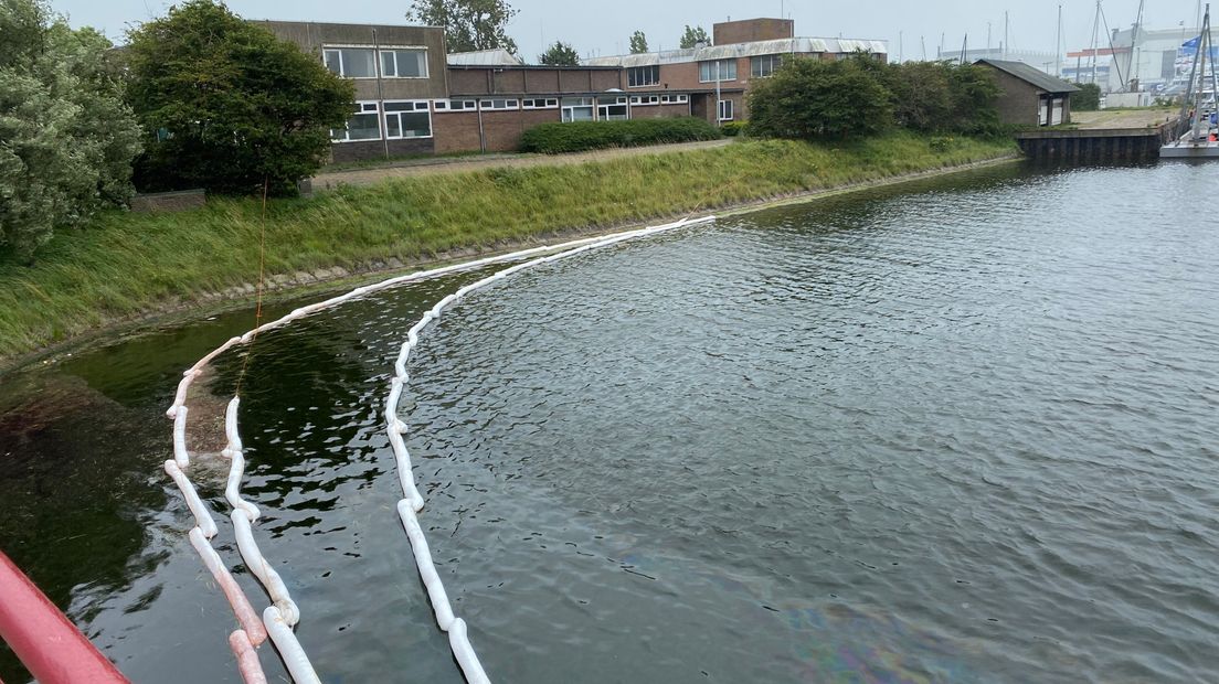 Olie booms liggen in het water om de olie in te dammen