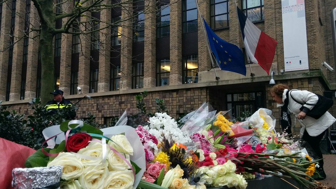 Mensen leggen bloemen bij de Franse ambassade