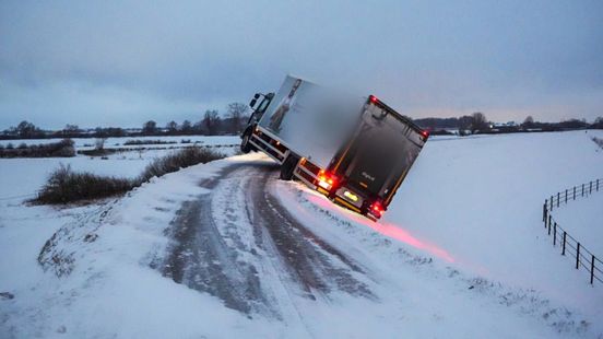 Vrachtwagen glijdt van gladde dijk