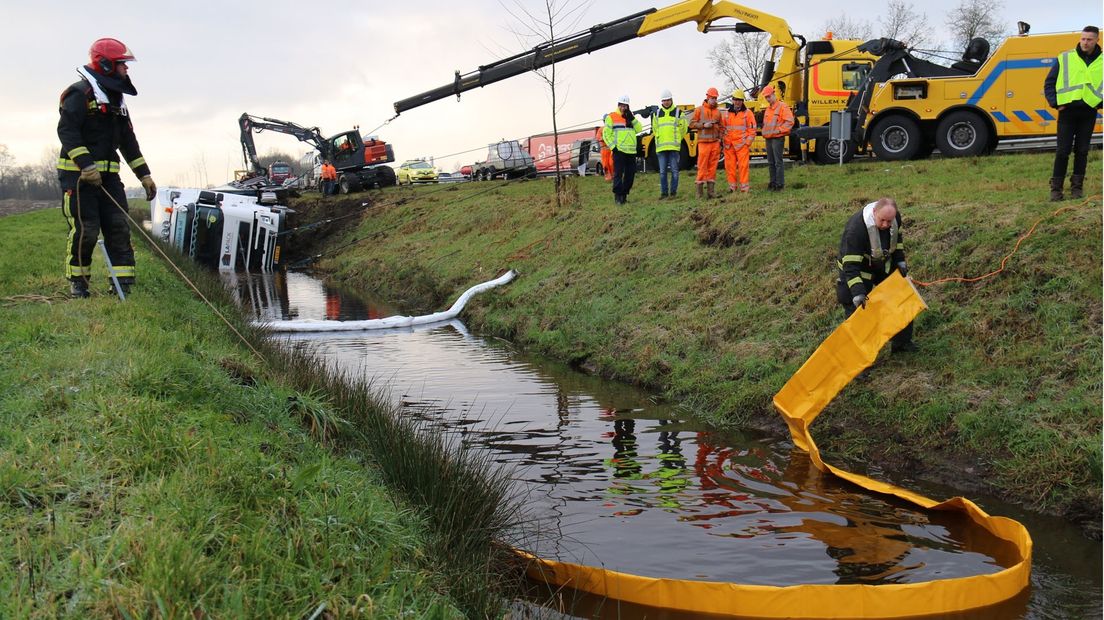 Een kraan takelt de vrachtwagen uit het water