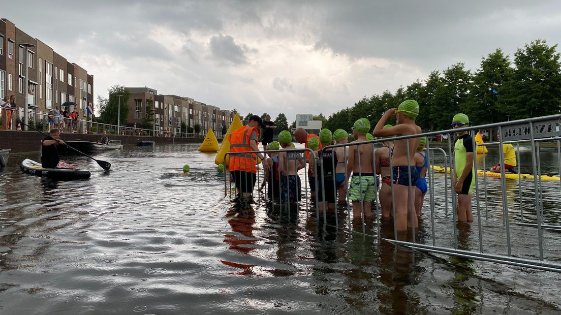 De eerste groep staat klaar. Ze gaan 75 meter zwemmen in een plas aan de Musicalkade. Deze 'groene badmutsen' zijn 8 en 9 jaar oud.