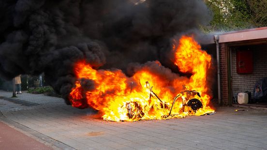Brommobiel in vlammen op, zwarte rookpluim boven woonwijk