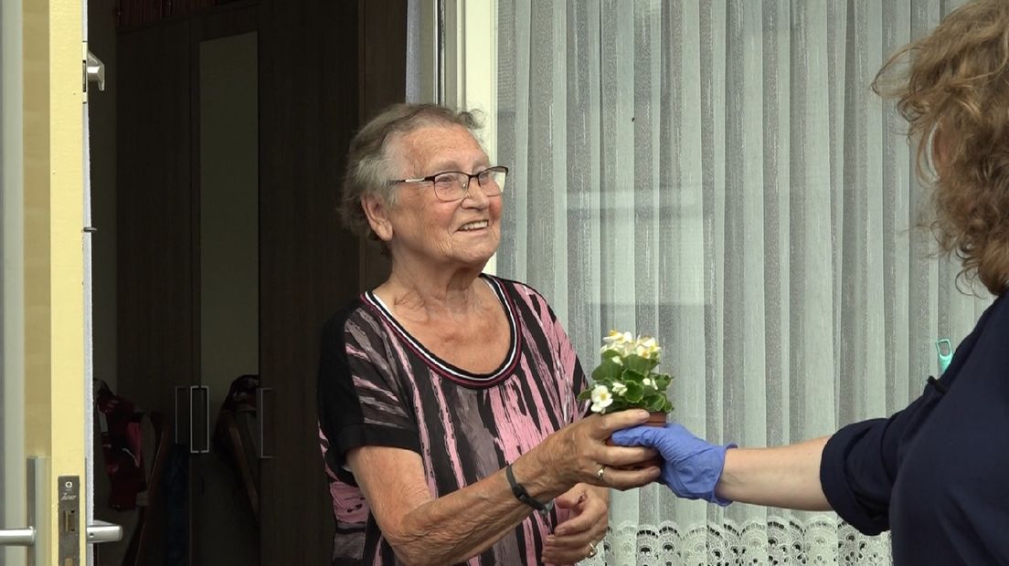 Een oudere vrouw wordt blij gemaakt met een plantje.