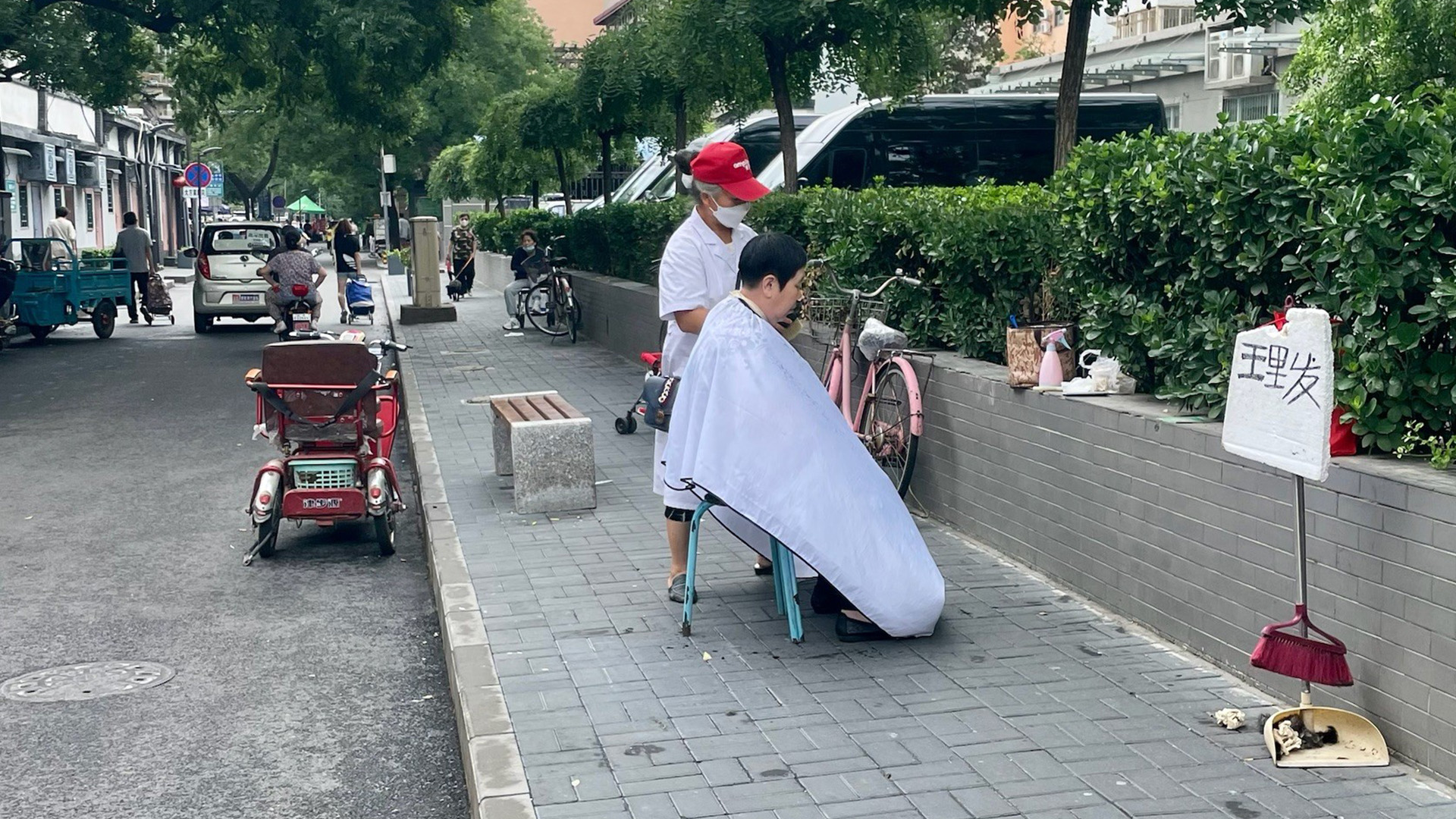 Kapper in Beijing op straat aan het knippen