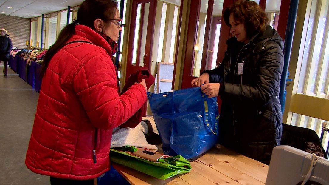 Boodschappentassen vol tweedehands kleding gaan over de toonbank