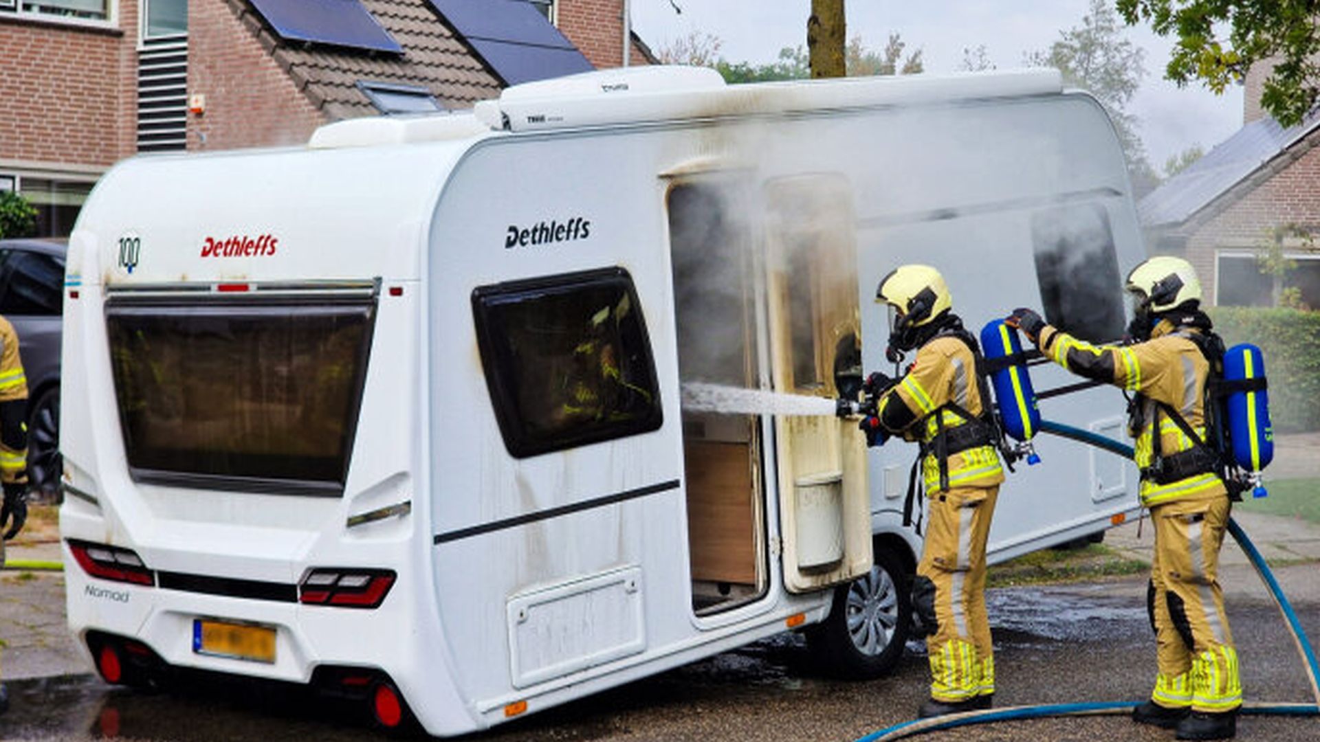 Buurman en brandweer blussen caravanbrand