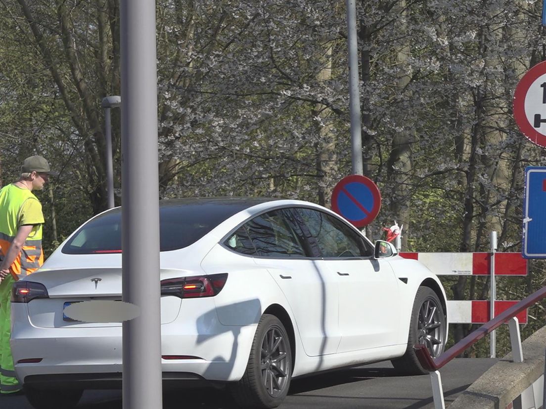 Parkeerwachter houdt ter hoogte van Plaszoom een auto tegen om het Kralingse Bos in te gaan