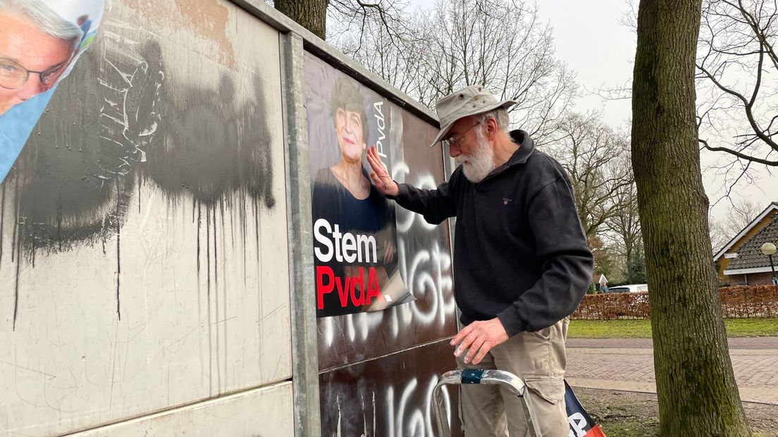 Theo Claas, lokale PvdA plakt zijn posters op de aanplakmuur.