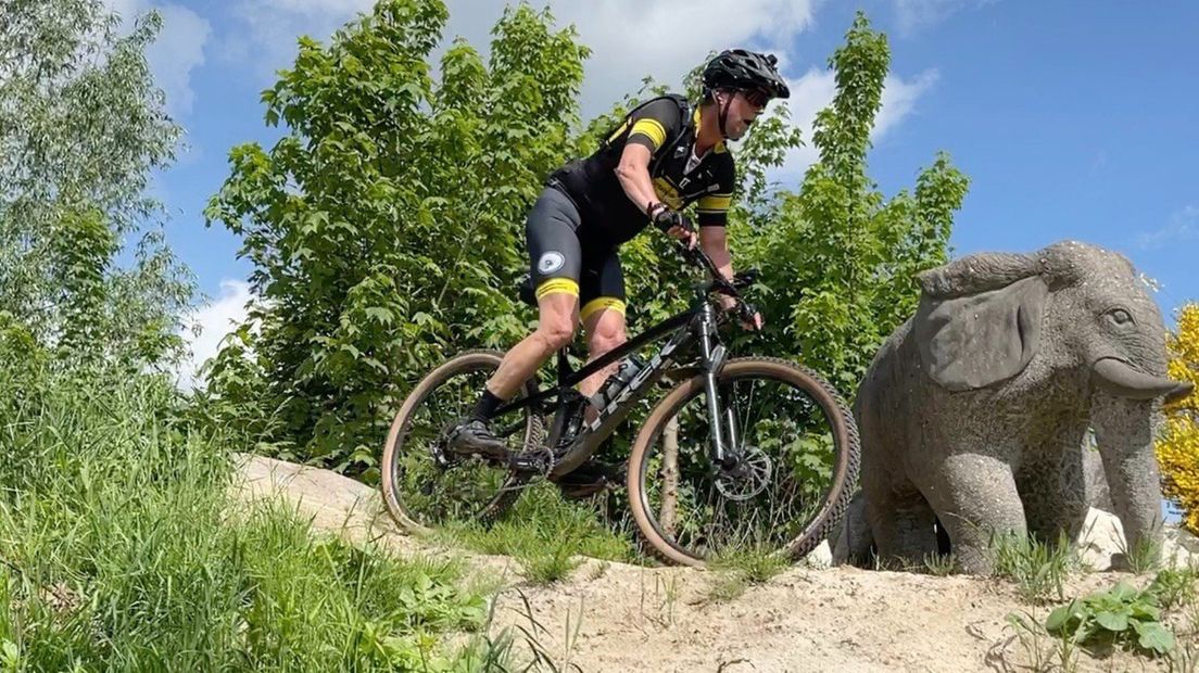 Een mountainbiker neemt een hindernis in het bikepark in Nuis