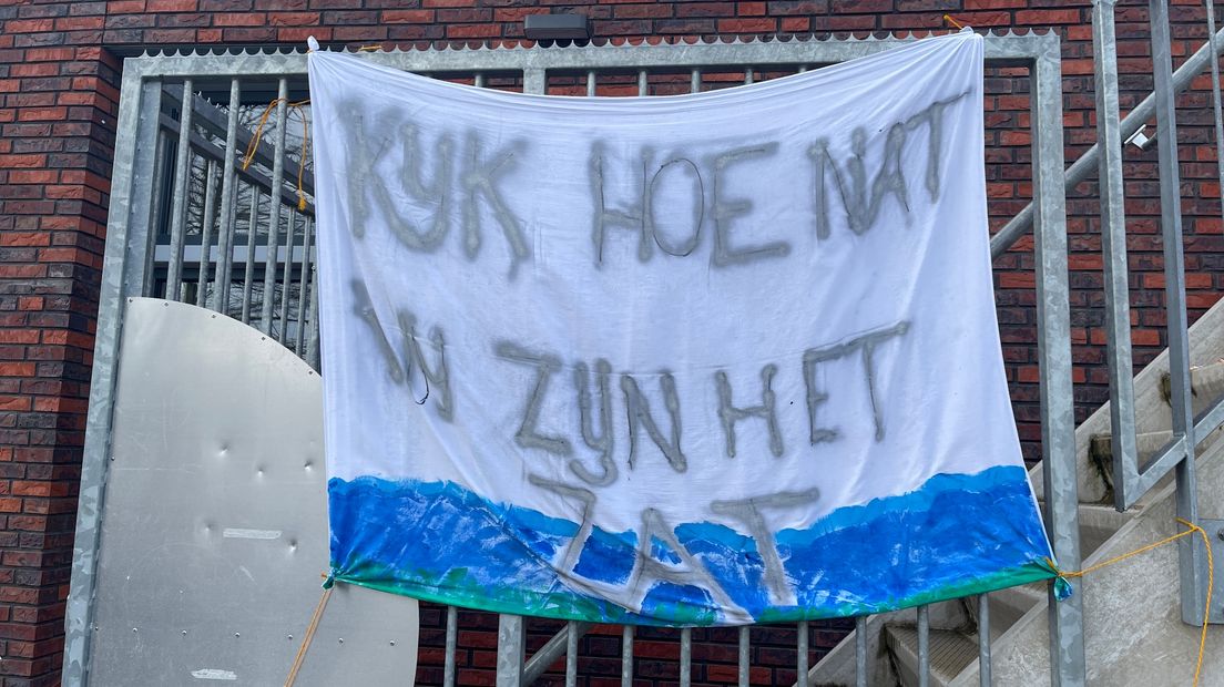 Protestspandoek met de tekst 'Kijk eens hoe nat, we zijn het zat'