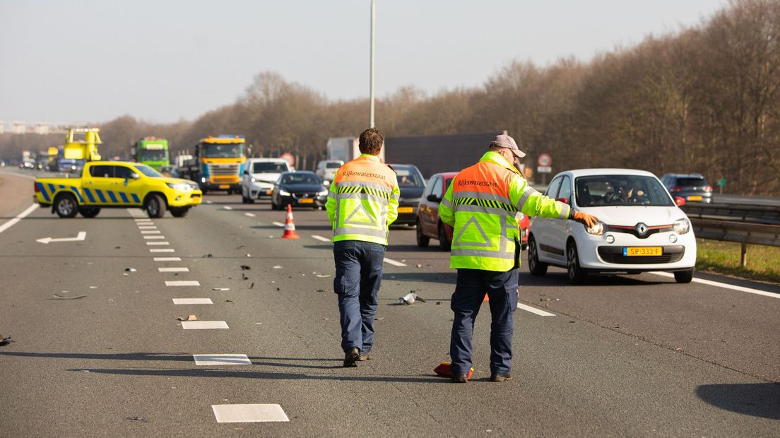 Weginspecteurs van Rijkswaterstaat maken een wegdek schoon na een ongeval.