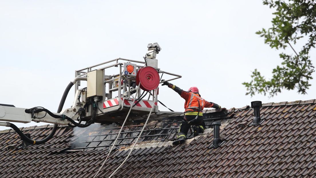 Een brandweerman komt met een hoogwerker op het dak