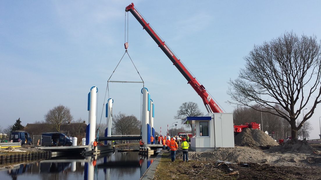 Een kraan plaatst het nieuwe brugdeel