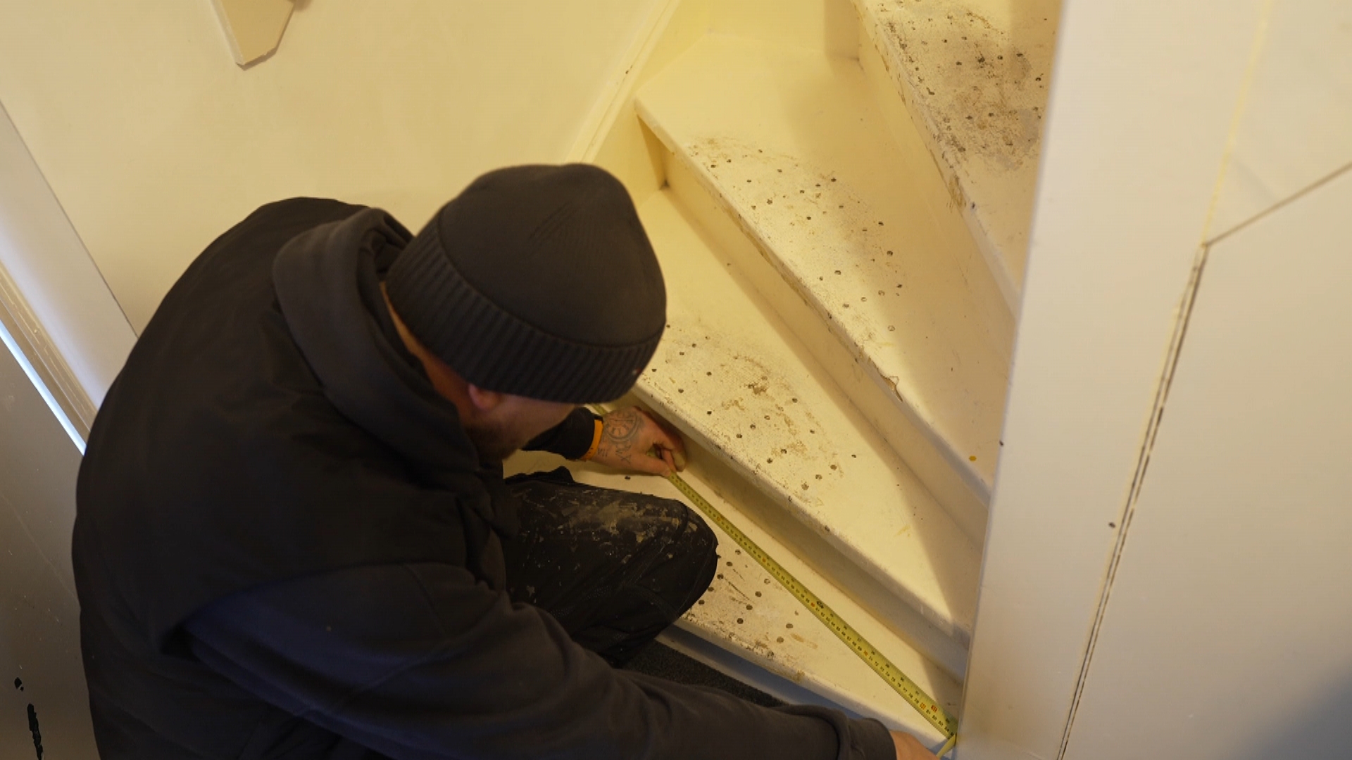 De stoffeerder neemt de maten van de traptredes op.