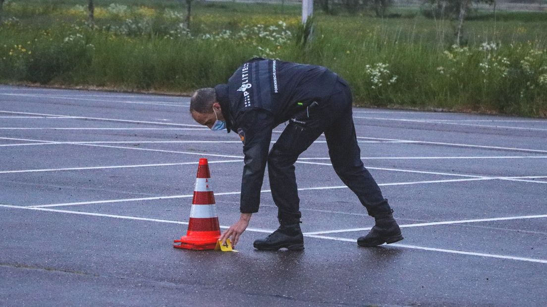 Een agent doet sporenonderzoek op de parkeerplaats