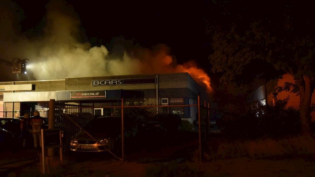 Vlammen slaan uit het dak van autobedrijf Bcars in Hengelo