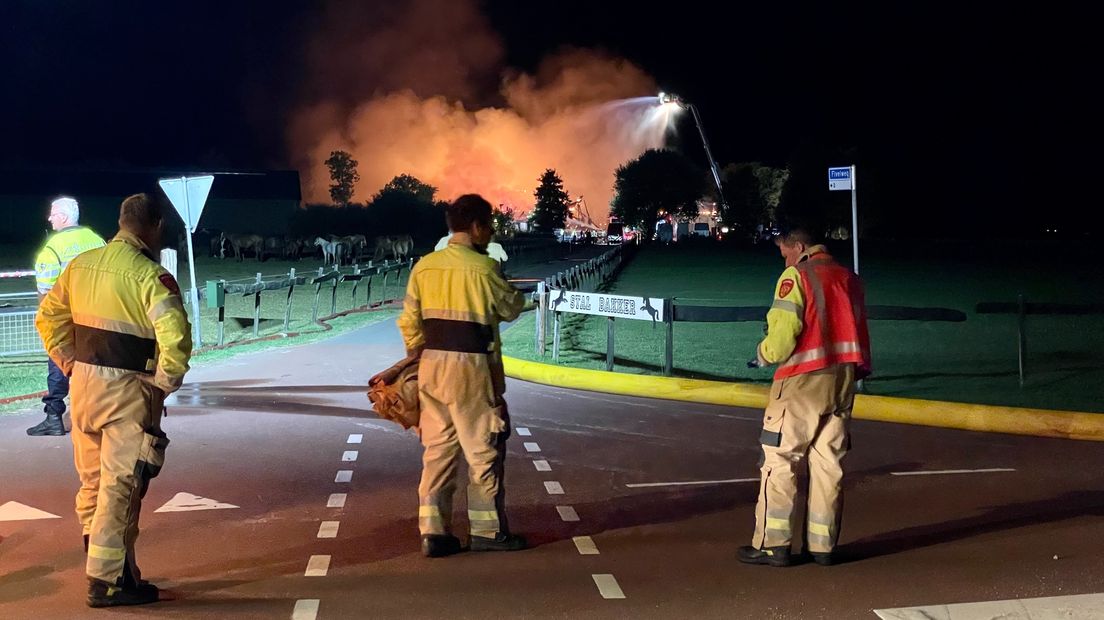 Enkele brandweerlieden kijken van een afstand toe bij de brand in Zijldijk