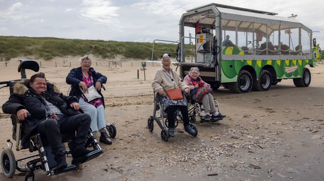 Deelnemers strandrupsrit staan met hun rolstoel op het strand
