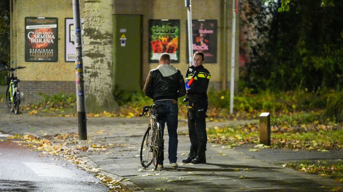 Een agente bekeurt een fietser in Groningen