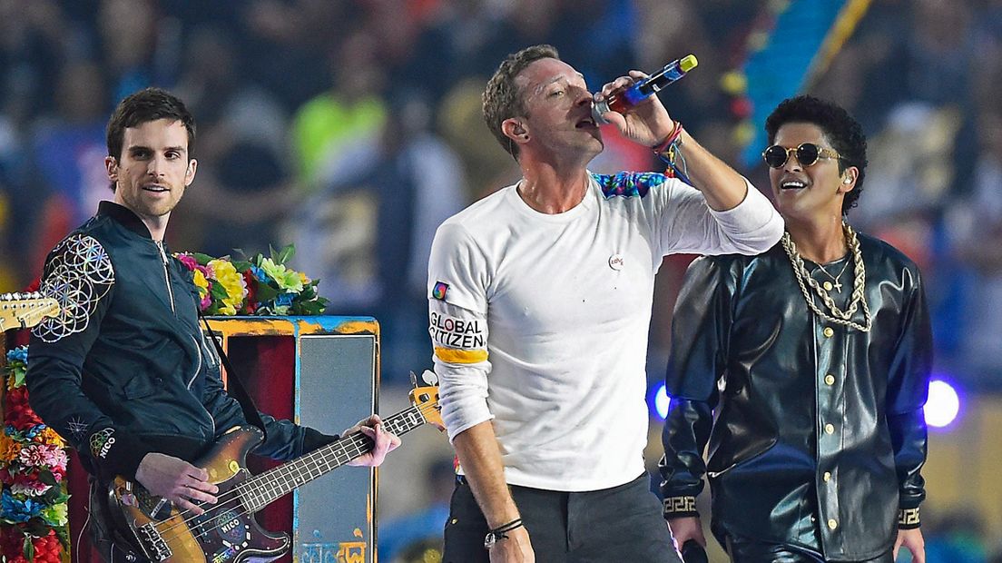 Guy Berryman (L), samen met Coldplay-zanger Chris Martin (M) en zanger Bruno Mars tijdens de 'halftime show' van de Amerikaanse Super Bowl 2016. 