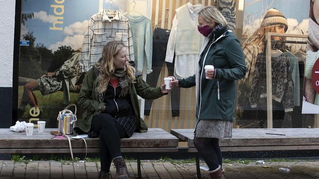 Twee vriendinnen drinken samen een kopje koffie in de Herestraat in Stad