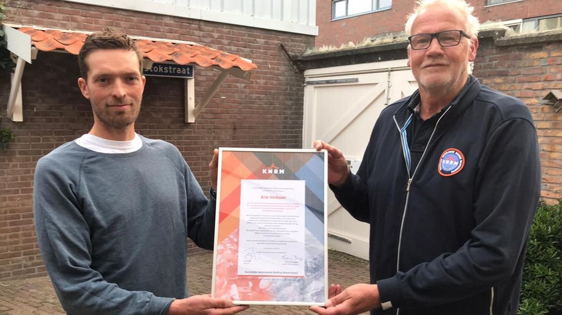 Geredde surfer Ruurd overhandigt oorkonde aan Arie Verbaan, van de KNRM