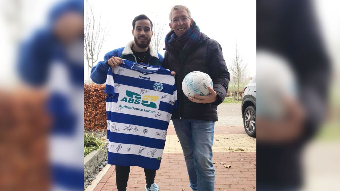 Jordy Tutuarima, voetballer van De Graafschap, overhandigt een gesigneerd clubshirt aan Roel Eefting, fractievoorzitter van D66.