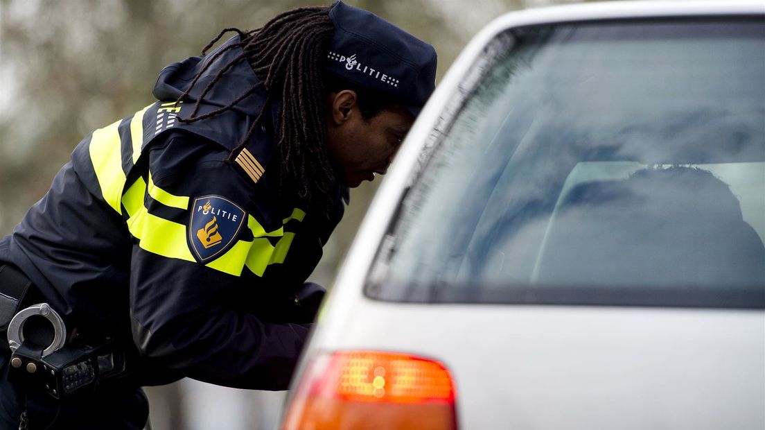 Een politieagent controleert het rijbewijs en kentekenbewijs van een automobilist (archief).