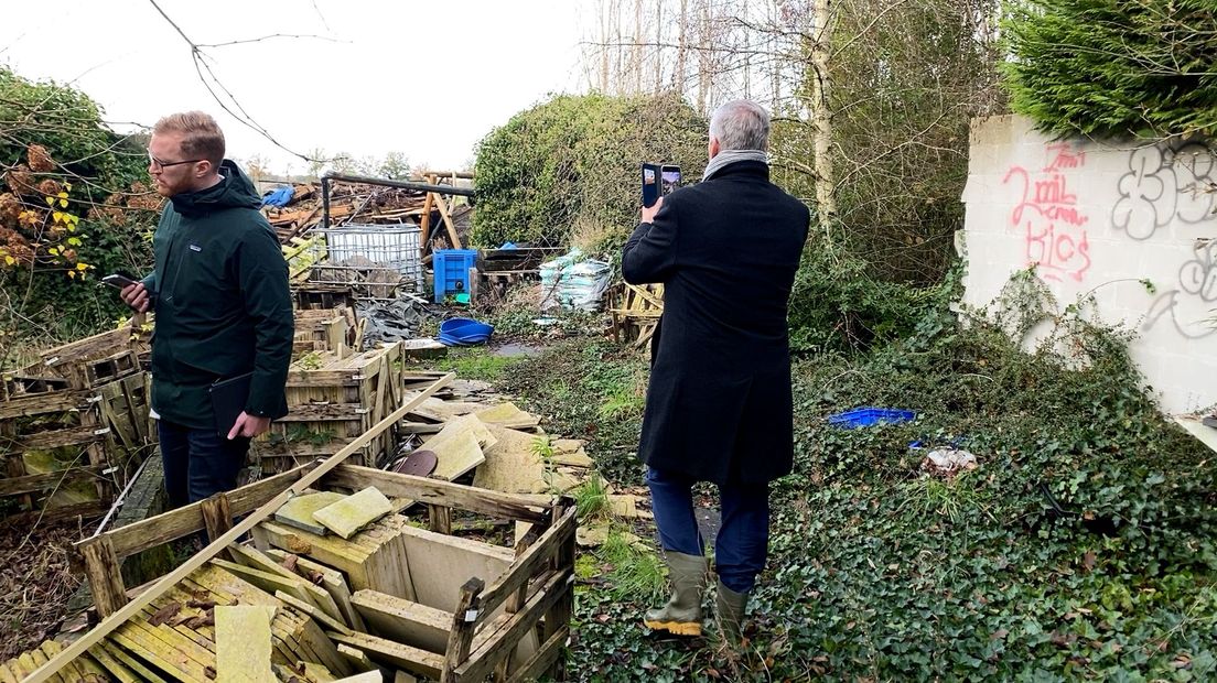 Burgemeester Frits Naafs maakt foto's in de tuin waar het voormalige drugslab verstopt was