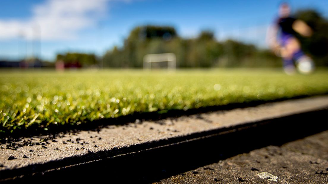 Een voetbalveld van kunstgras met rubberkorrels.