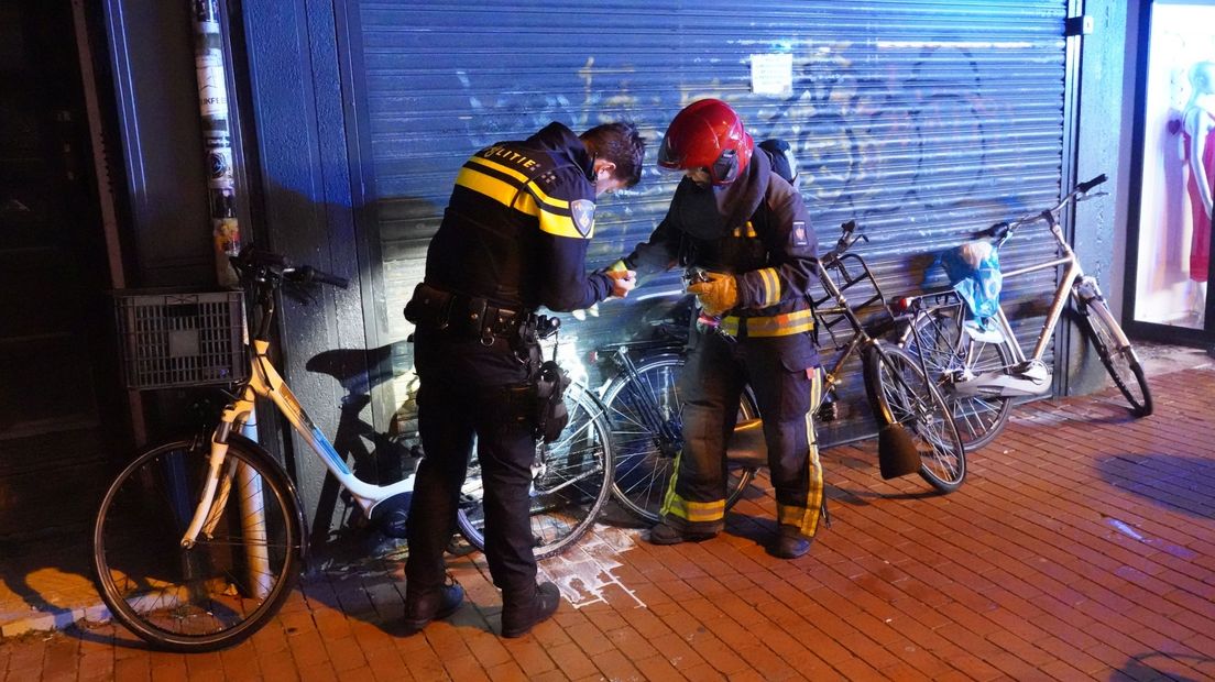 Een politieagent en een brandweerman onderzoeken gezamenlijk de licht ontvlambare fiets