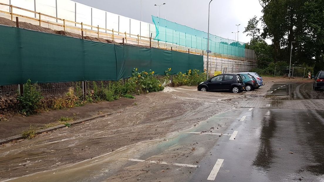 Het weggestroomde zand vanuit het talud ligt op de weg