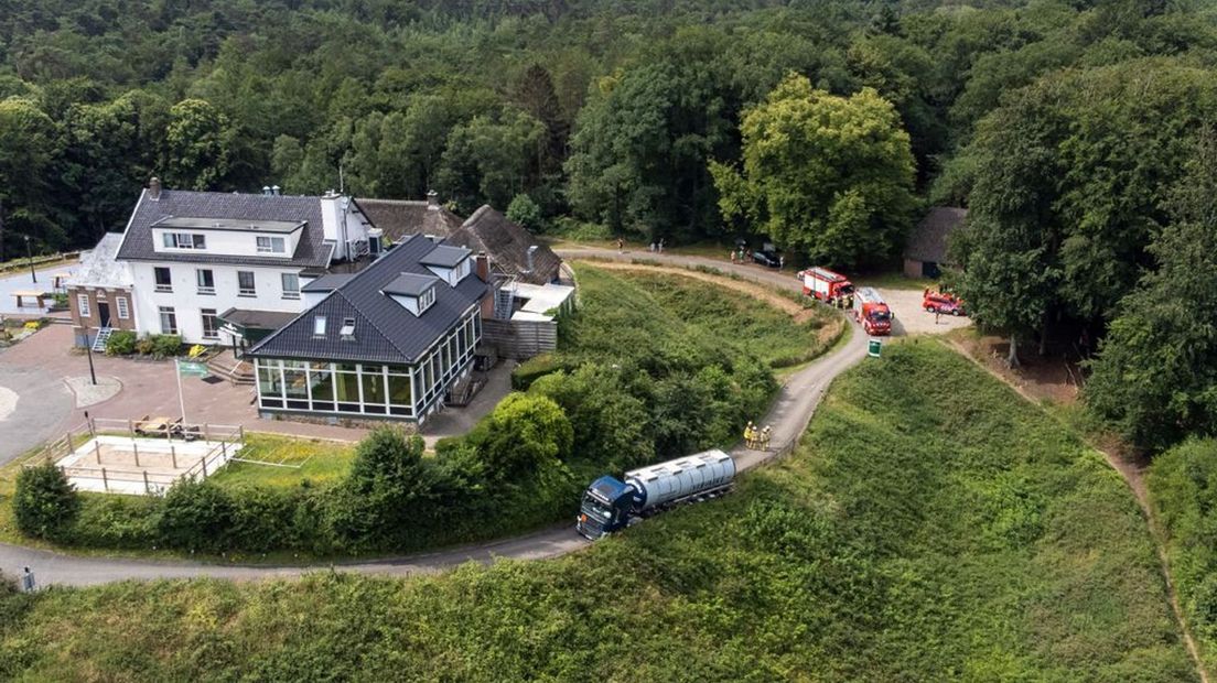 De vrachtwagen zit vast in de berm in een bocht die steil omhoog loopt.