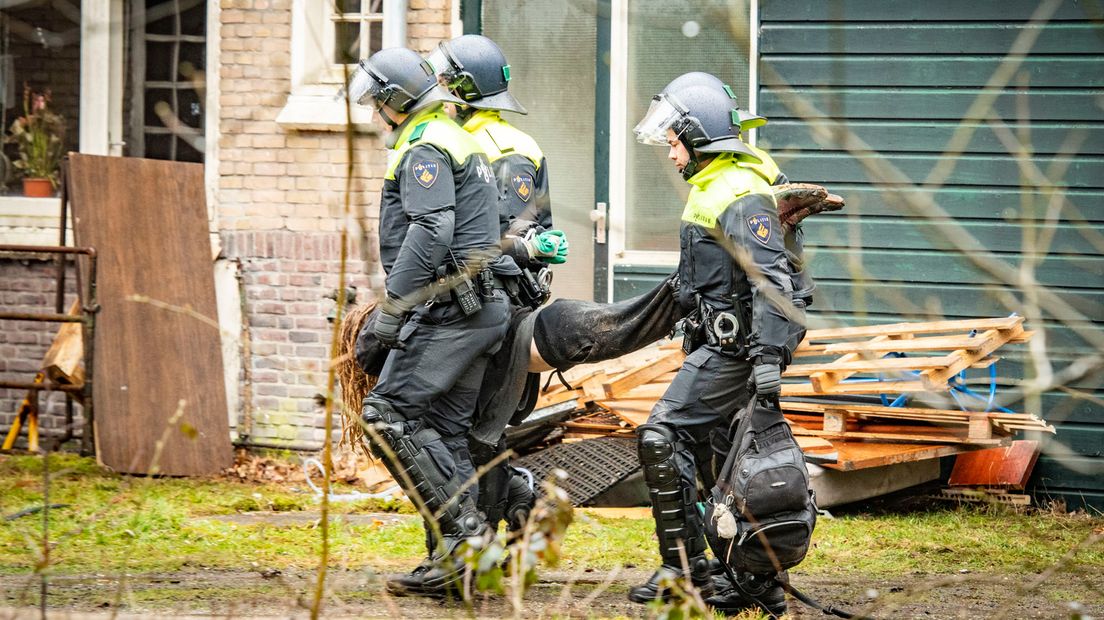 Een persoon wordt afgevoerd door de politie.