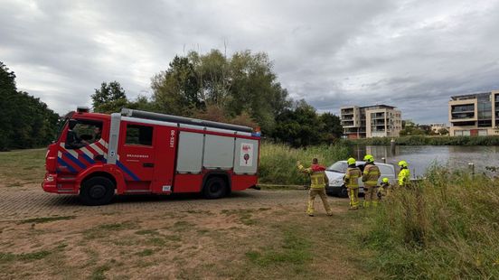 Auto met trailer rolt het water in