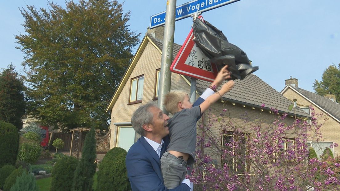 Wethouder Uitslag onthult het verkeersbord samen met een kleuter