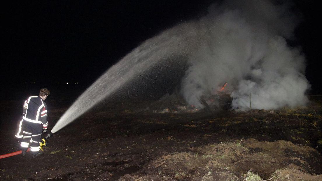Een brandweerman blust het paasvuur in Emmer-Compascuum (Rechten: Van Oost Media)