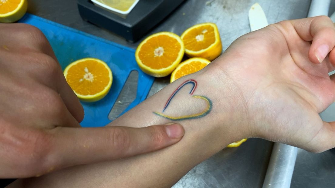 Orysia laat haar tatoeage zien van een hartje met de kleuren van de Nederlandse en Oekraïense vlag