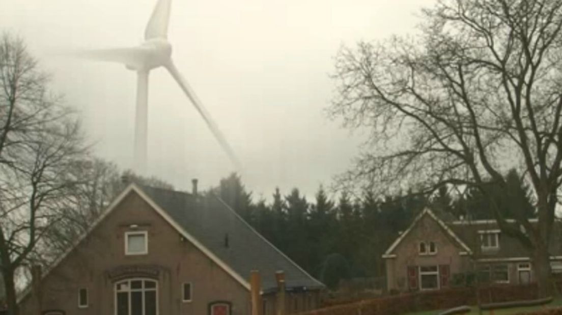 Trucagefoto van een windmolen die boven het Veluwse bos uitkomt.