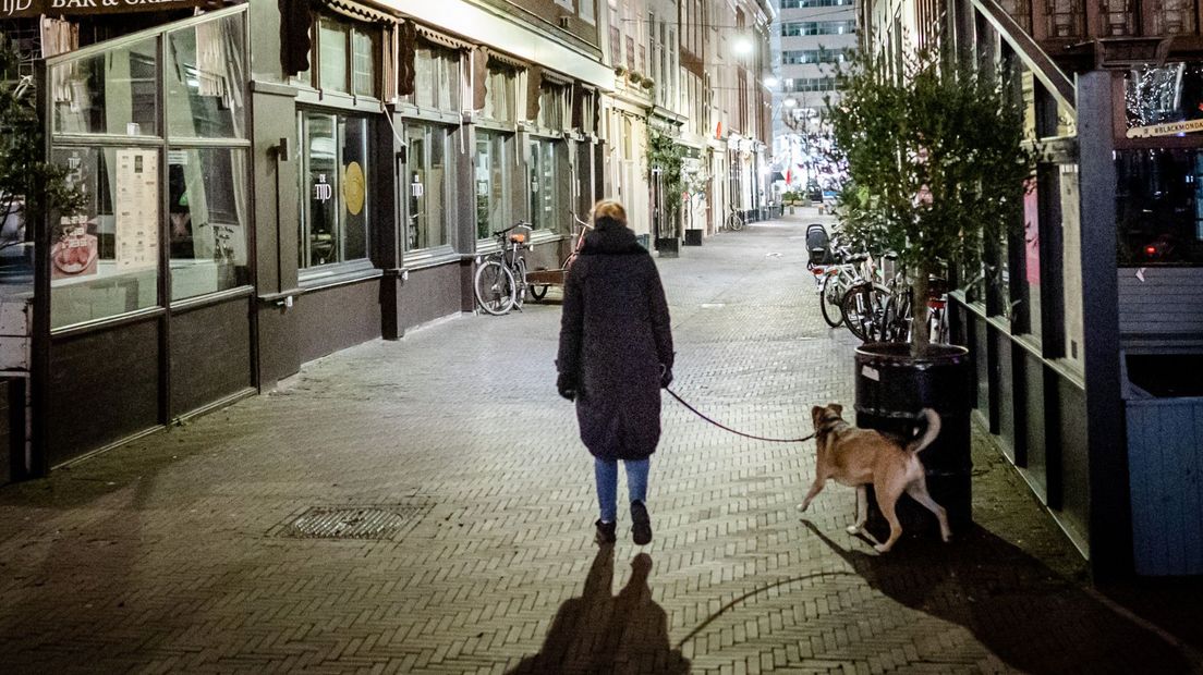Een vrouw laat haar hond uit tijdens de avondklok
