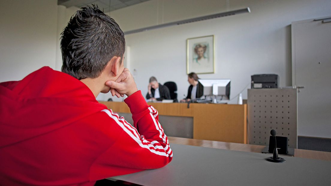 Een jongen luistert in de rechtbank naar het oordeel van de rechter.