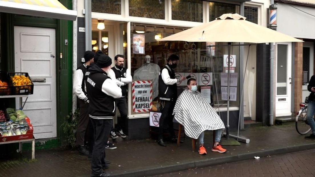 Op de stoep voor kapperszaak Barberstation in Klarendal in Arnhem wordt een klant gratis geknipt.
