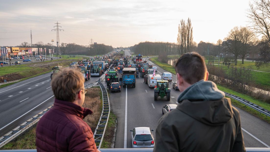 Twee toeschouwers kijken naar het boerenprotest op de A28