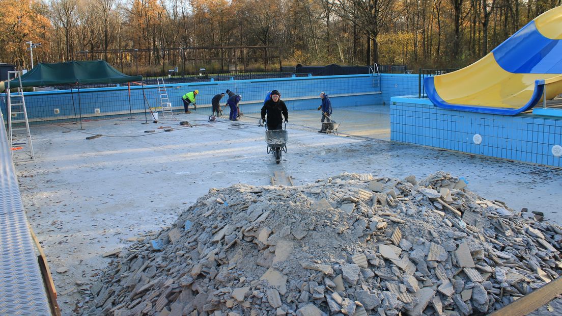 Vrijwilligers zijn druk bezig om de 20.000 tegels uit het zwembad in Ruinen te halen