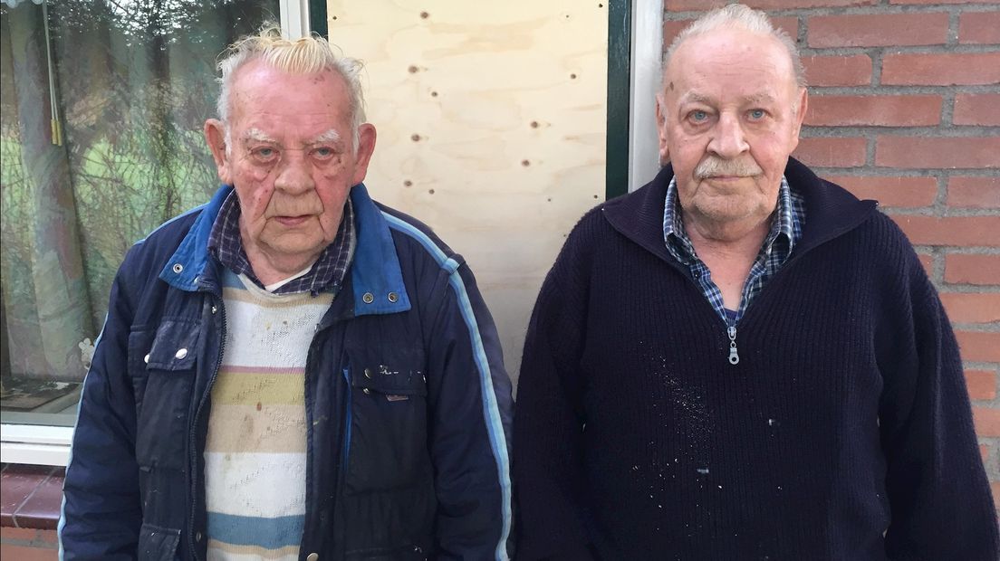 Hein (87) en Frans (73) voor het inmiddels dichtgetimmerde raam waardoor de overvallers binnenkwamen