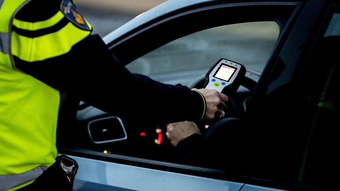 Een politieagent laat een bestuurder blazen voor een alcoholtest.